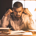 Man sitting at a desk, fists clenched
